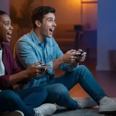 Coppia entusiasta gioca ai **giochi PS5 per 2 giocatori** sul divano, controller alla mano, immersi nell'azione.