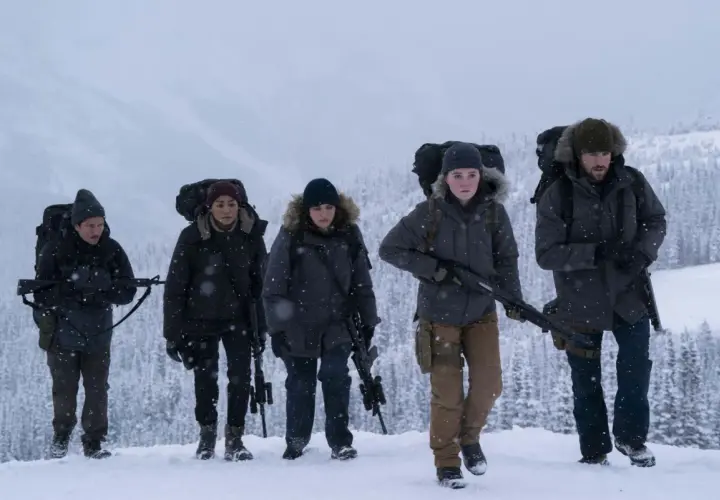Un gruppo di sopravvissuti armati cammina nella neve, un'immagine che evoca la tensione di "the last of us 3".