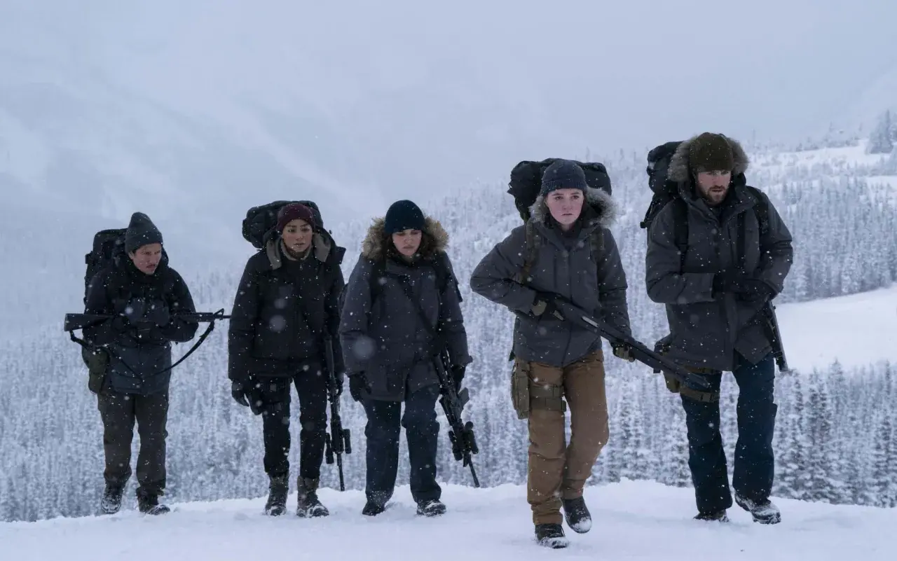 Un gruppo di sopravvissuti armati cammina nella neve, un'immagine che evoca la tensione di "the last of us 3".